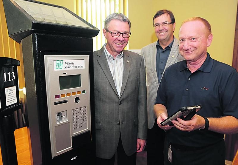 Le programme d’implantation des horodateurs a été présenté par le maire de Saint-Hyacinthe, Claude Corbeil, le directeur général, Louis Bilodeau et le directeur du service des Travaux publics, Yvan De Lachevrotière. Il tient ici la tablette numérique de contrôle qui guidera les proposés au stationnement vers les voitures des contrevenants. L’amende pour stationnement impayé demeurera de 15 $. Photo Robert Gosselin | Le Courrier ©