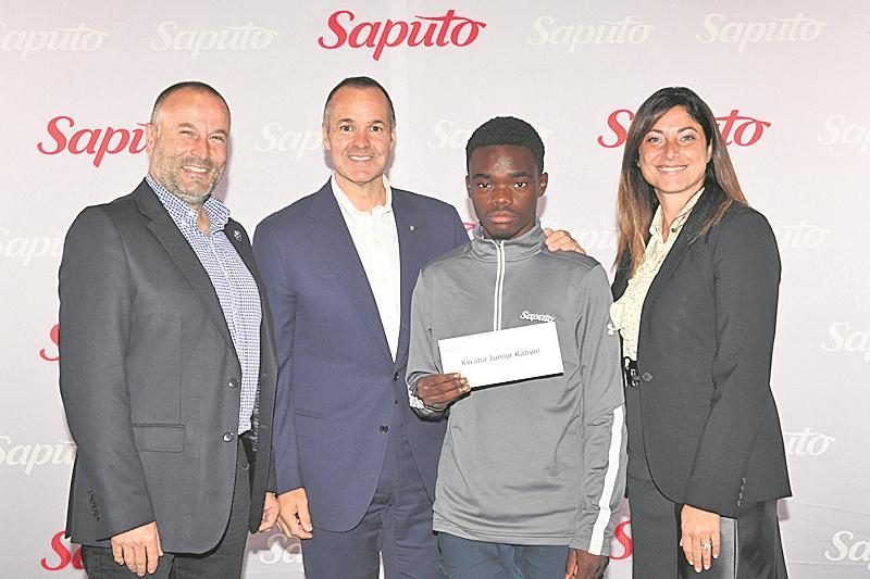 Sur la photo, Junior Kabwe est accompagné du directeur de l’Académie de l’Impact, Philippe Eullaffroy, du président de l’Impact de Montréal, Joey Saputo, et de la vice-présidente communications et responsabilité corporative de Saputo, Sandy Vassiadis.  Photo courtoisie Groupe NH Photographe