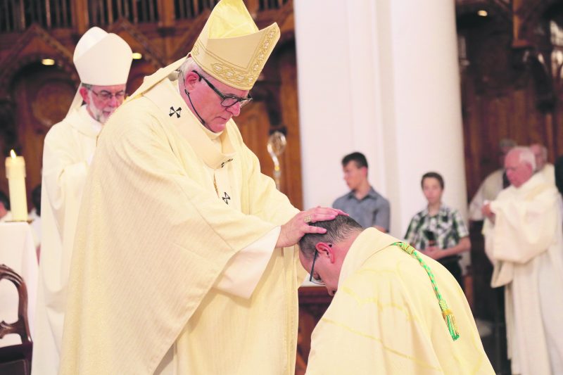 Mgr Luc Cyr, archevêque de Sherbrooke, accomplit le rite de l’imposition des mains à Mgr Rodembourg lors de son ordination. Chacun des nombreux évêques présents a fait le même geste à sa suite pendant la cérémonie. Photo Robert Gosselin | Le Courrier ©