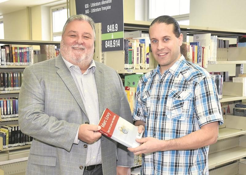 Le directeur de l’école Casavant Sylvain Fugère accepte volontiers les centaines de livres offerts par l’ancien étudiant Frédéric Fortin, maintenant propriétaire de Les Trésors du futur à Beloeil.  Photo François Larivière | Le Courrier ©
