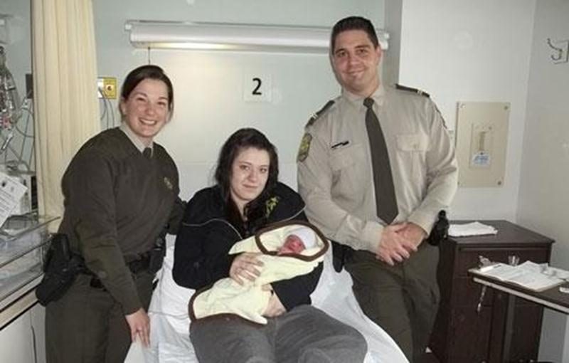 L'agente Karine Michel et le sergent Alexandre Turgeon entourent la jeune maman et son nouveau-né.