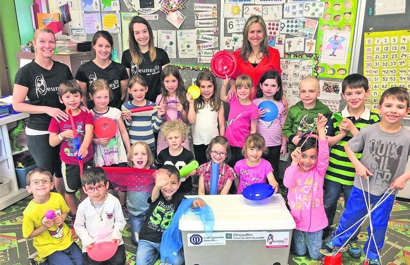 Les trois intervenantes en psychomotricité de Jeunes en santé : Véronique Laramée, Josée-Anne Paquette et Marilyne Lalumière posent en compagnie de Martine Laliberté, enseignante à l’école Bois-Joli/Sacré-Coeur, et d’élèves de la maternelle montrant fièrement les nombreux accessoires contenus dans un bac.