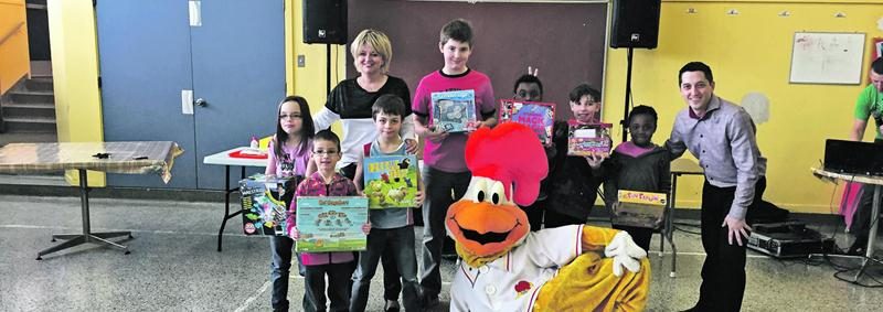 Nancy Greenland, de la Fondation FÉE, et Steve Deslauriers, de la Rôtisserie Saint-Hubert, ainsi que la mascotte Hubert, accompagnent les élèves qui ont remporté des jeux éducatifs.