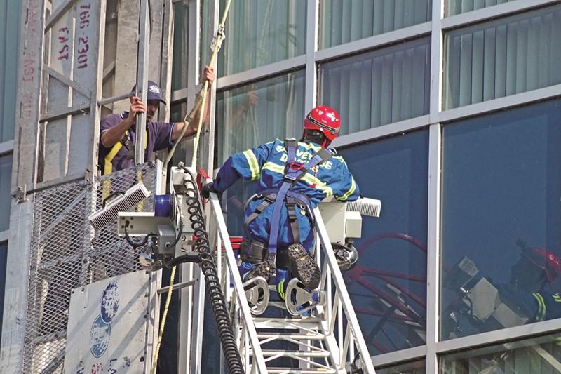 L’un des deux employés prisonniers de la nacelle attend d’être secouru par les pompiers. Photo Dominique St-Pierre