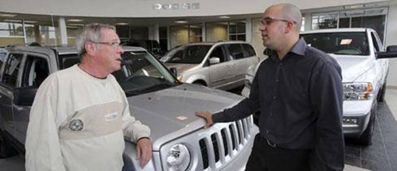 Un représentant de chez Chrysler en compagnie d'un client en ce premier samedi d'ouverture pour le concessionnaire du boulevard Choquette.