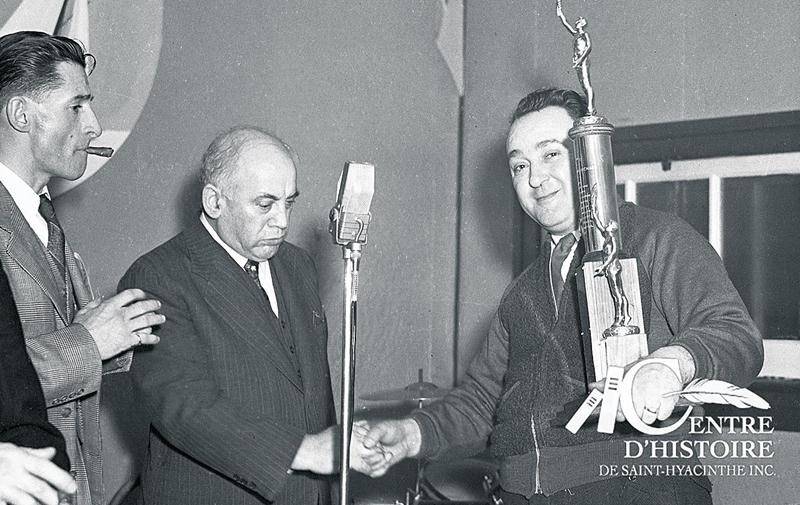 Lors de la remise de prix, en 1950, Gérard Côté observe le sénateur T.D. Bouchard qui donne la main à Césaire Vermeersch, responsable du bon déroulement de la soirée. Photo Collection Centre d’histoire de Saint-Hyacinthe, CH548.