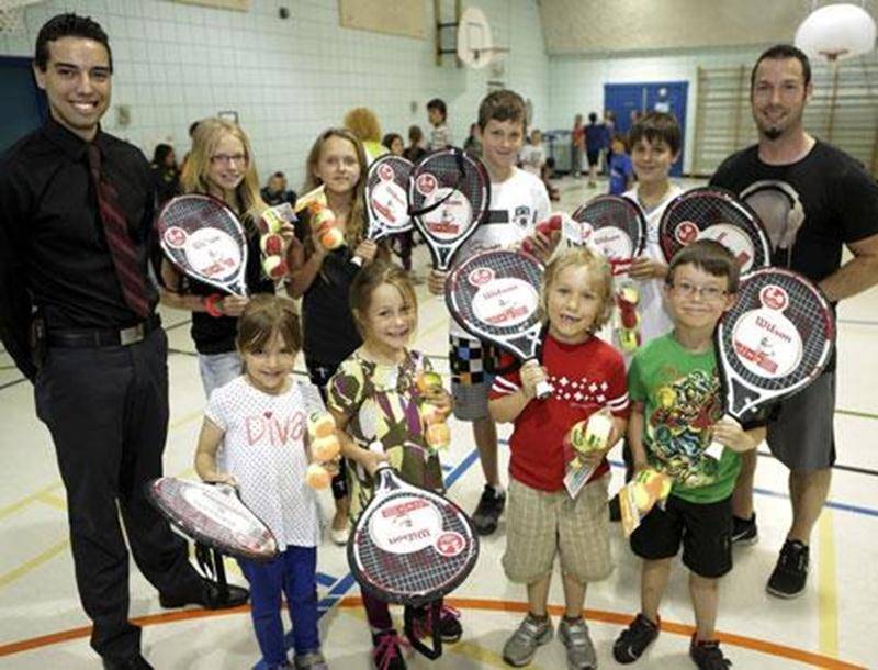Sur la photo on aperçoit Michael Lapierre, directeur des opérations au Canadian Tire Saint-Hyacinthe, remettant un ensemble de tennis aux élèves de l'école de la Rocade.