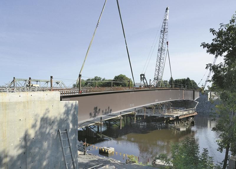 L’assemblage des poutres d’acier au-dessus de la rivière Yamaska va bon train au chantier du pont Bouchard. Chaque section est livrée par fardier depuis Saint-Nazaire, au Saguenay-Lac-Saint-Jean.