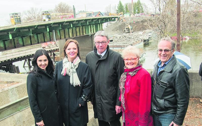 La ministre Lucie Charlebois, responsable de la région de la Montérégie (deuxième à partir de la gauche), était à Saint-Hyacinthe lundi pour procéder au lancement officiel du projet de reconstruction du pont Bouchard. Elle est entourée ici de la députée de Saint-Hyacinthe, Chantal Soucy, du maire Claude Corbeil et des conseillers municipaux Johanne Delage et Jacques Denis. Comme on le voit ici, la démolition du vieux pont était très avancée lundi. Photo François Larivière | Le Courrier ©