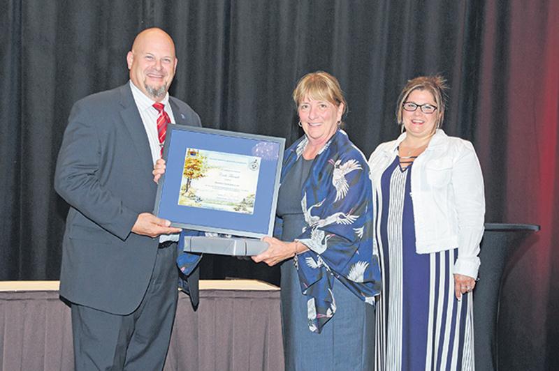 Cécile Tétreault est entourée de Jonathan Nyborg, président de l’Association canadienne des producteurs de semences, et de la conjointe de celui-ci, Denise Nyborg, lors de la remise de son prix en juillet. Photo courtoisie