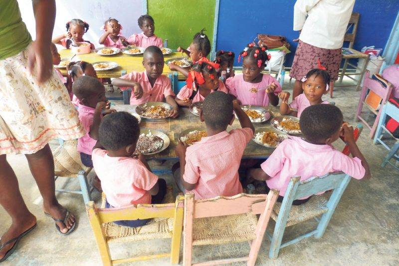 Des écoliers en train de prendre leur repas grâce aux cantines scolaires, qui constituent un incitatif fort à la présence en classe. Photo gracieuseté