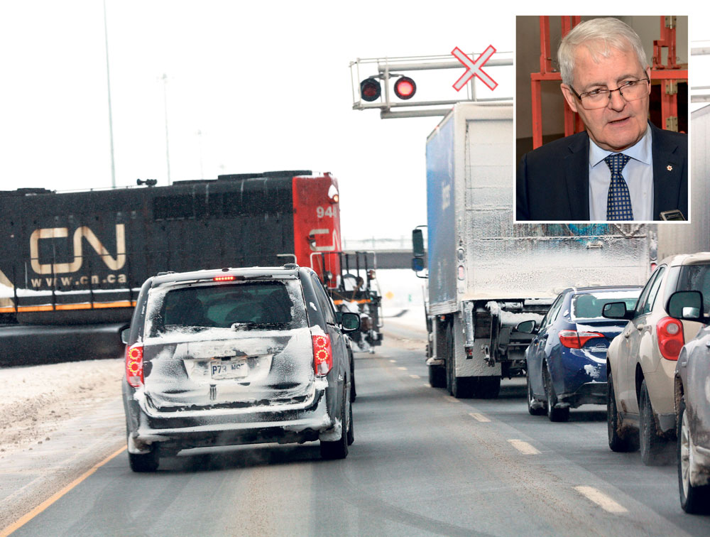 Deux fois par jour, le trafic de l’autoroute 20 à la hauteur de Saint-Hyacinthe est arrêté plusieurs minutes pour permettre le passage d’un train de marchandises en direction du parc industriel Théo-Phénix. En mortaise, le ministre fédéral des Transports, Marc Garneau, lors d’un récent  passage à Saint-Hyacinthe. Photo Robert Gosselin | Le Courrier © 