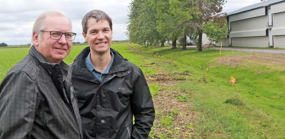 Mario Dupont et Joël Leblanc, producteurs agricoles de la région. On remarque derrière eux des plantations d’arbres qui visent à créer un brise-vent et l’utilisation de radis comme engrais vert dans le champ. Photo Robert Gosselin | Le Courrier ©