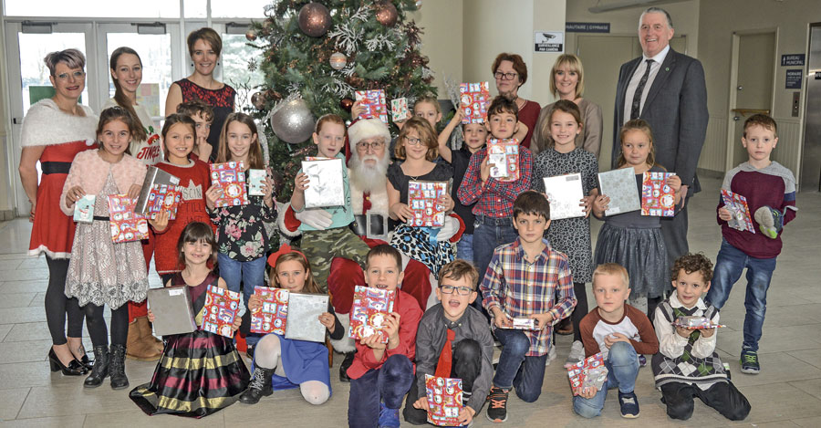 Le père Noël pose en compagnie de quelques-uns des 173 jeunes de Sainte-Hélène-de-Bagot qui ont reçu un beau cadeau lors de la journée du dépouillement de l’arbre de Noël du 18 décembre. Derrière eux, on reconnaît aussi Kathleen Marcoux, directrice du Comité des loisirs Sainte-Hélène, Olivia Bourque, coordonnatrice des loisirs, Hélène Laforest, directrice de l’école Plein-Soleil, Sylvie Goupil, professeure à l’école Plein-Soleil, Nathalie Witty, adjointe à la direction générale de la Caisse Desjardins Seigneurie de Ramezay, et Normand Choquette, directeur général de la Caisse Desjardins Seigneurie de Ramezay, qui ont rendu cette activité possible. Photo François Larivière | Le Courrier ©