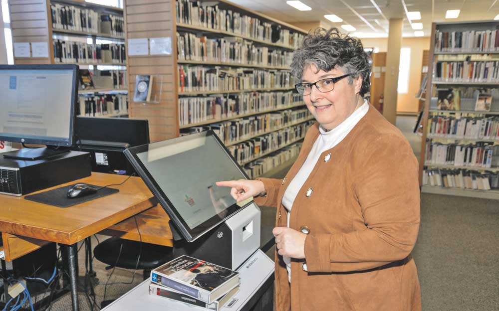 La directrice générale de la Médiathèque maskoutaine, Louise Struthers, à l’une des nouvelles bornes d’auto-prêt. Photo François Larivière | Le Courrier ©