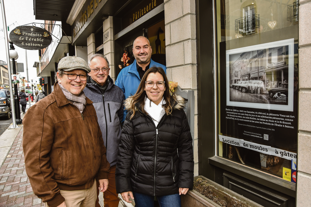 De nouvelles images d’époque ont pris place dans la vitrine de certains commerçants du centre-ville dans le cadre du projet de « musée à ciel ouvert ». Sur la photo, on aperçoit Paul Foisy et Daniel Girouard, respectivement directeur général et aide-archiviste du Centre d’histoire de Saint-Hyacinthe, en compagnie d’André Marcotte et Coralie Nault, respectivement directeur général et coordonnatrice aux événements de la SDC centre-ville. Photo François Larivière | Le Courrier ©