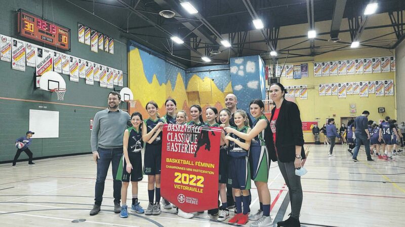 L’équipe féminine de basketball mini de l’école aux Quatre-Vents avec la bannière de championnesdu tournoi de Victoriaville. Photo gracieuseté