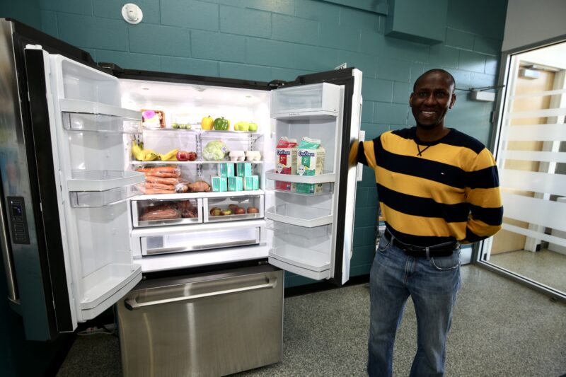 L’organisateur communautaire du Centre intégré de santé et de services sociaux de la Montérégie-Est Bruno Dioma montre un exemple de ce qu’on peut trouver dans un des réfrigérateurs alimentaires lors du lancement du projet. Photo Robert Gosselin | Le Courrier ©