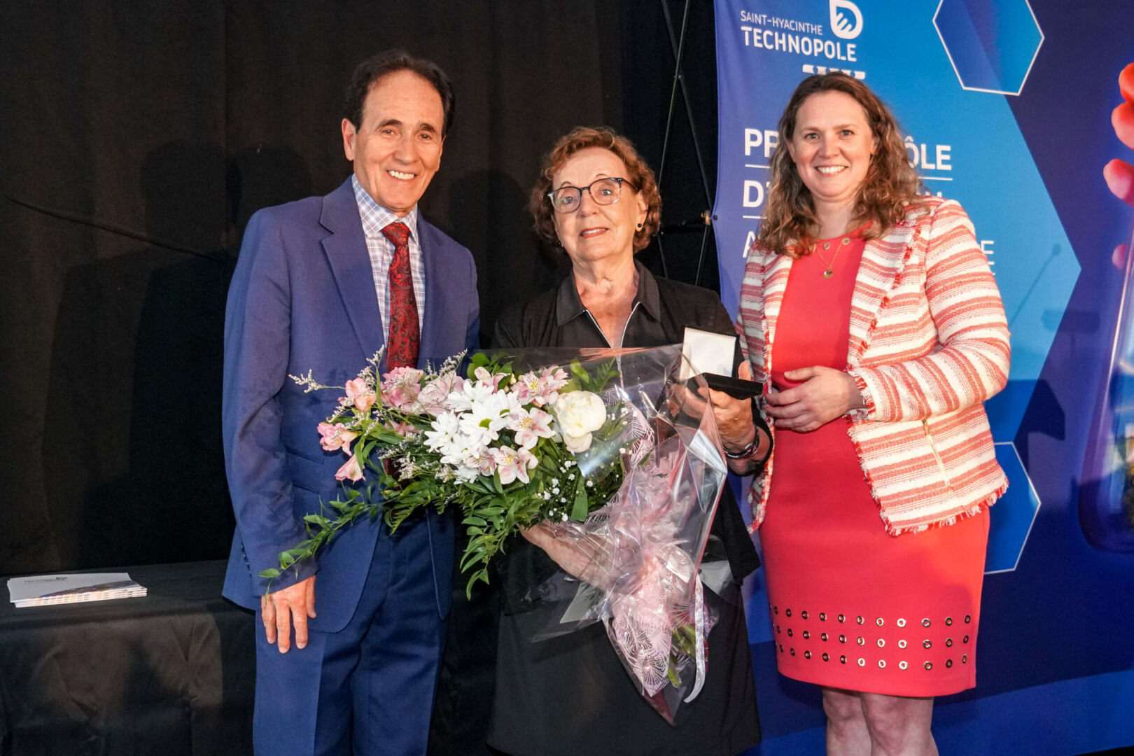 Le président et la directrice générale de Saint-Hyacinthe Technopole, Bernard Forget et Karine Guilbault, ont profité de la cérémonie du 20e anniversaire de la Cité de la biotechnologie agroalimentaire et vétérinaire de Saint-Hyacinthe pour remettre une médaille commémorative à Estelle Huot, épouse de Léandre Dion, père fondateur de la Cité, décédé en octobre dernier. Photo François Larivière | Le Courrier ©