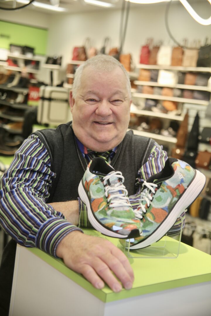 Le 16 octobre, André Bouthat, artiste-peintre vivant avec un trouble de santé mentale et membre du Trait d’union montérégien, s’est vu remettre une paire de chaussures par la boutique Chaussures à vos pieds sur laquelle une de ses toiles a été reproduite. Photo Robert Gosselin | Le Courrier ©