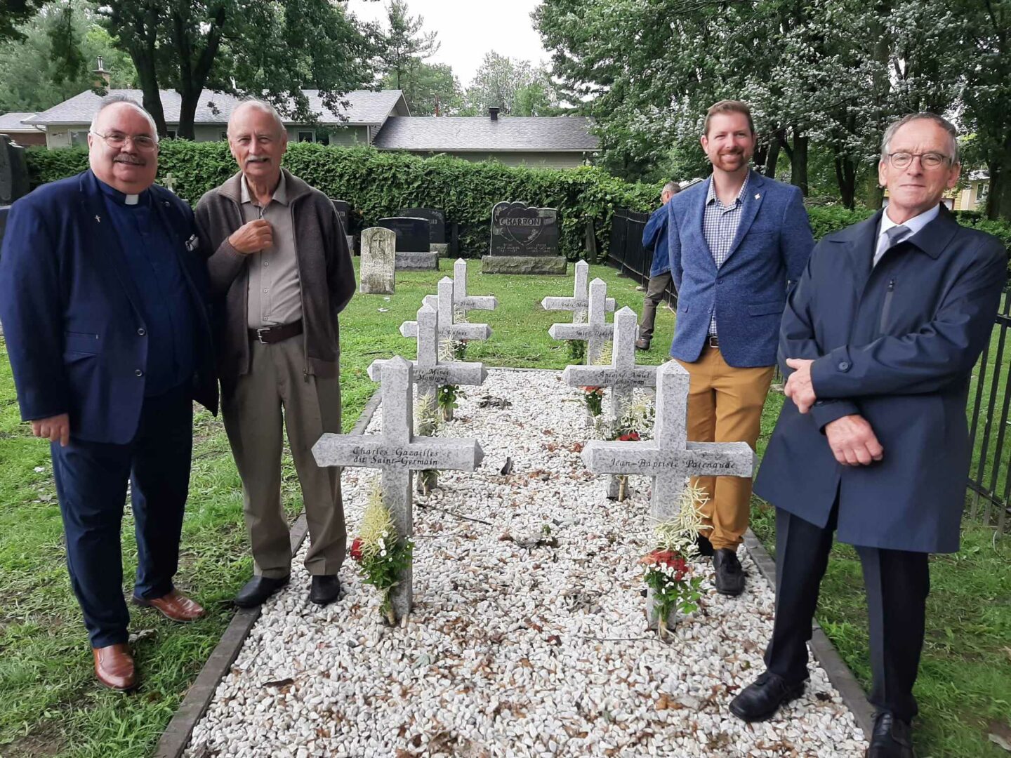 Le curé Pierre Cordeau, le Dr Patrick Binay, le député de Pierre-Boucher–Les Patriotes–Verchères, Xavier Barsalou-Duval, et le président de la Société d’histoire des Riches-Lieux, Guy Archambault, posent près des huit croix en granite érigées en hommage aux huit patriotes de Saint-Denis-sur-Richelieu morts au combat en novembre 1837. Photo Vincent Guilbault | Le Courrier ©