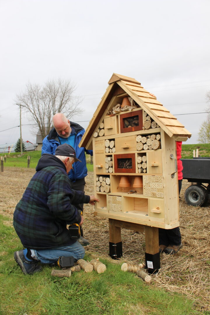 En plus de la plantation, le COBAVERCO installera des structures favorisant la biodiversité telles que cet hôtel de pollinisateurs. Sur la photo, Sylvain Nichols, propriétaire du terrain et producteur agricole, et Patrick Couture, coordonnateur d’Opération PAJE dont les jeunes participants ont construit l’hôtel. Photo gracieuseté