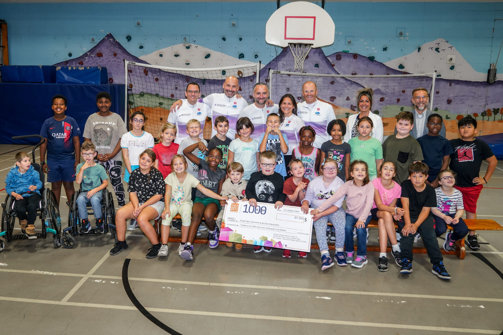 Des employés de Raymond Chabot Grant Thornton qui ont pris part au Grand défi Pierre Lavoie posent en compagnie d’élèves de l’école Saint-Sacrement lors de la remise du chèque de 31 355 $. Photo François Larivière | Le Courrier ©