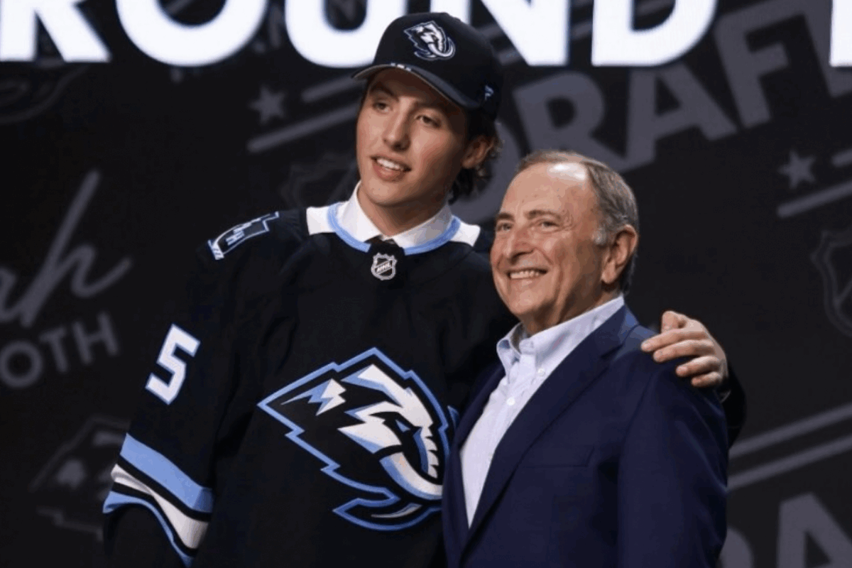 Caleb Desnoyers a été sélectionné au 4e rang du repêchage de la LNH par le Mammoth de l’Utah. On le voit aux côtés du commissaire de la ligue, Gary Bettman, dans son nouvel uniforme. Photo LNH / Utah Mammoth